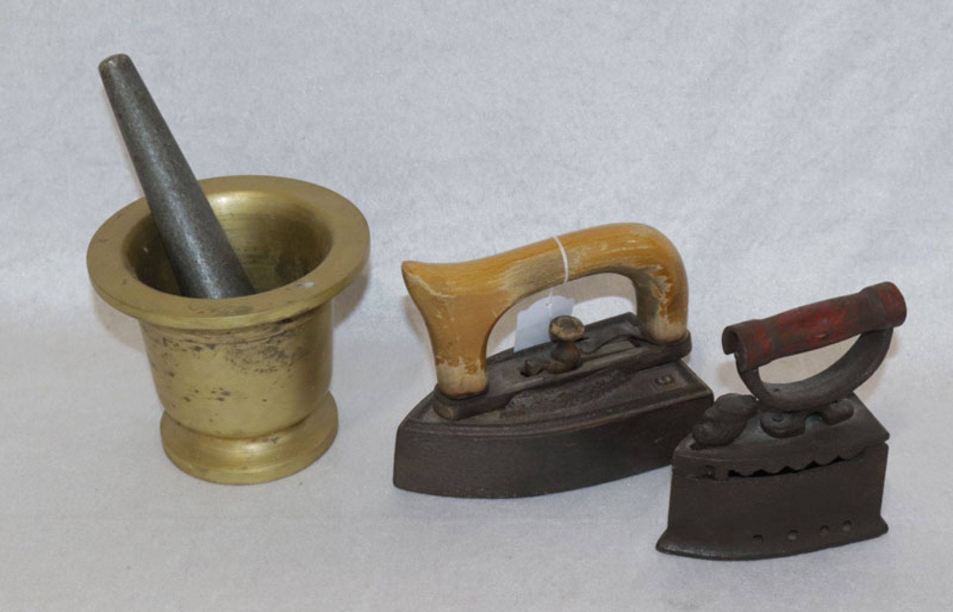 Konvolut: Metall Mörser mit Stößel, H 12 cm, D 14 cm, und 2 antike Bügeleisen mit Holzgriffen, H