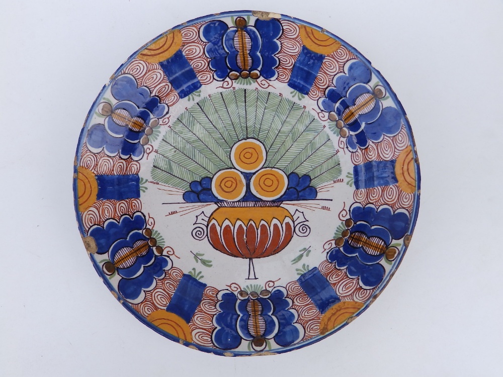 An 18thC polychrome delft charger, decorated with a stylised peacock medallion to centre, in blue,