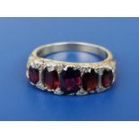 A graduated five stone garnet ring with diamond spacers in 18ct gold. Finger size O.