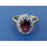 An oval garnet & diamond cluster ring in 18ct & PLAT. Finger size R/S.