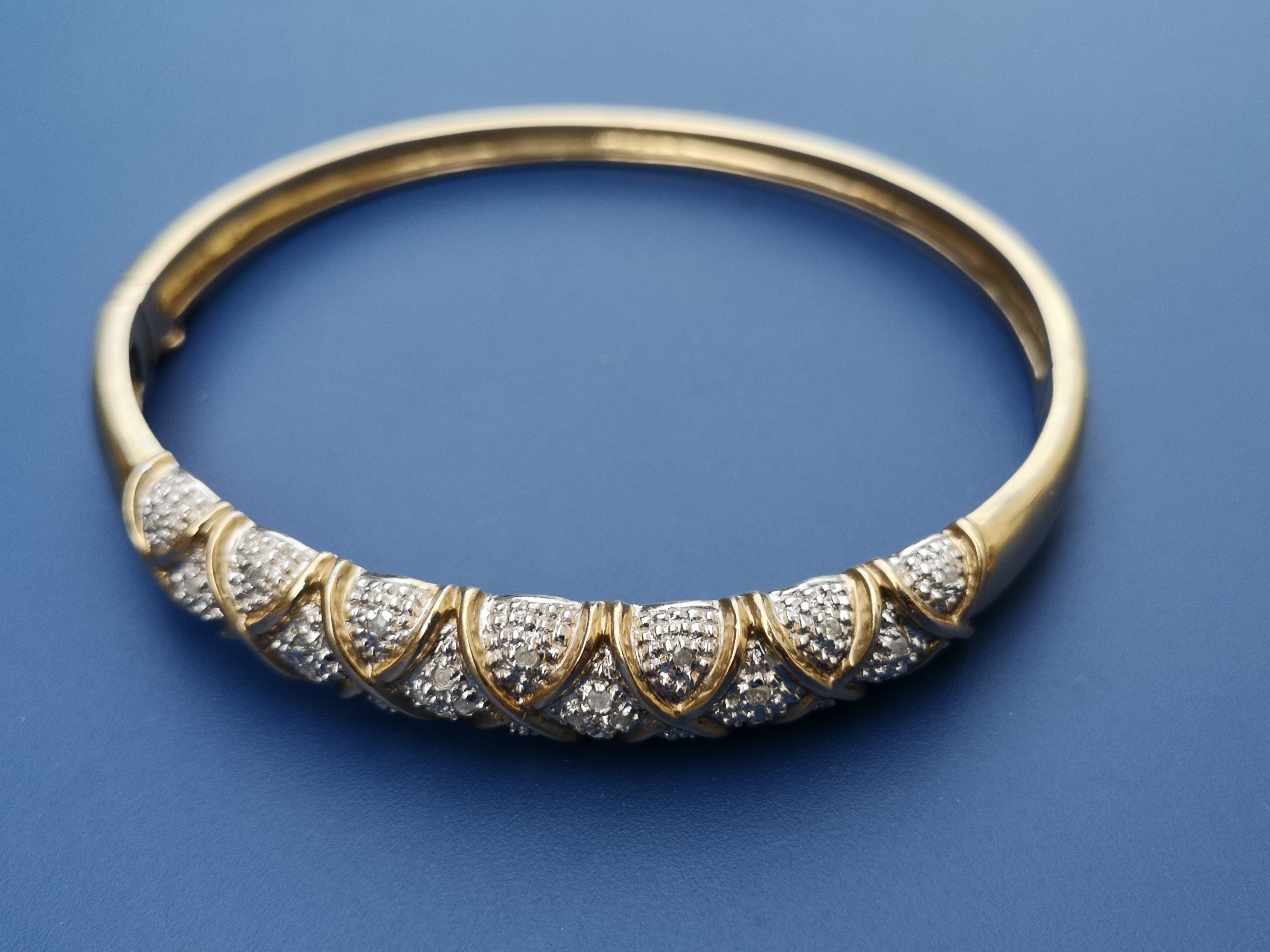 A modern diamond set 9ct bangle, 2.4" across.