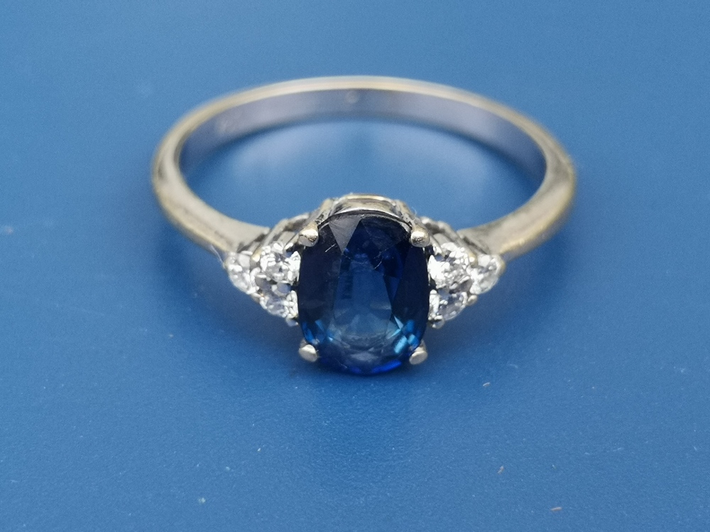 A modern sapphire & diamond set 18ct gold ring, the oval sapphire fanked by six small diamonds - '