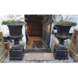 A pair of antique cast iron campana shaped garden urns on square pedestal bases, 27" high.