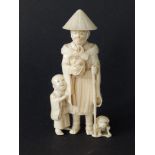 A Japanese Meiji period ivory okimono group depicting an old man holding a kitten with a young boy