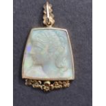 An art deco style carved opal 9ct gold pendant, relief decorated with a female head, 1.3" overall.