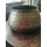 An Eastern embossed brass pot, decorated to sides with stylised script and animals, 12" diameter.