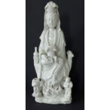 A large early Chinese blanc de chine porcelain figure of a seated Kuan Yin with two small dragons at