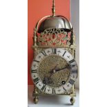 An antique brass bell-striking lantern clock, having dolphin cresting, the 6.25" dial with