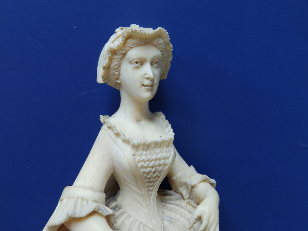 An antique carved ivory female figure, depicting a young woman in 18thC costume, holding a fan in - Image 2 of 6