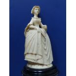 An antique carved ivory female figure, depicting a young woman in 18thC costume, holding a fan in