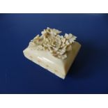 A late 19th/early 20thC small erotic carved ivory box, having raised flowers to detachable lid,