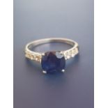 A modern sapphire solitaire ring, in four claw setting with small diamonds to shoulders, 14ct