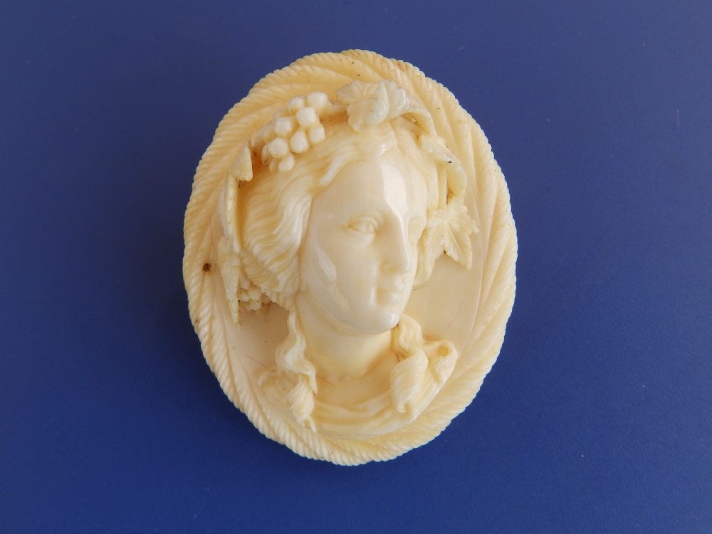 A Victorian oval ivory brooch carved in high relief with Bacchanalian female bust, 1.75" high.