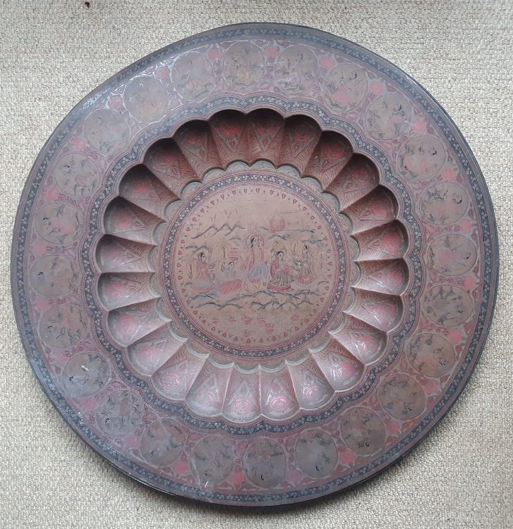 A large Indian brass tray, decorated overall in colours with detailed figures within panels, a