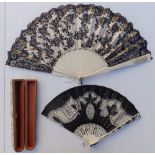 A 19thC ivory fan, the cream silk leaf decorated in black lace with sequins, an openwork monogrammed