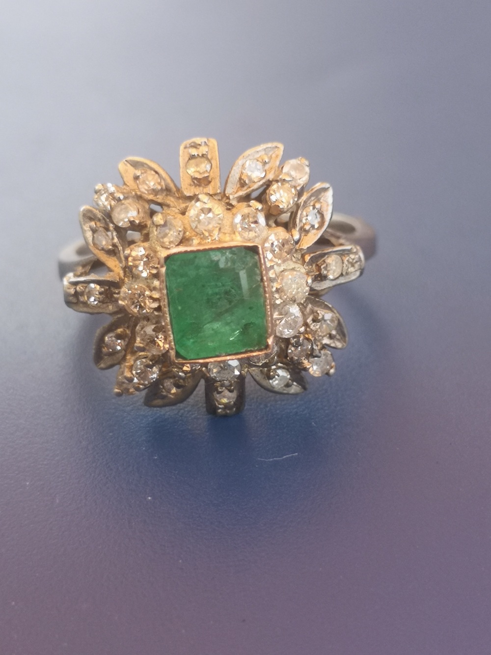 A modern emerald & diamond '750' cluster ring. Finger size P - emerald chipped.