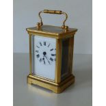 A brass carriage clock - 'ACCL' with white enamel dial, 4.25" high excluding handle.