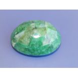 A large faceted oval specimen of opaque emerald with GLI (India), colour enhanced, 477 carats, 2.25"