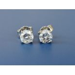 A pair of diamond solitaire stud earrings, each four-claw set brilliant weighing approximately 0.