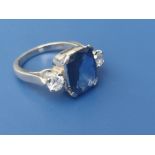 A sapphire & diamond three stone ring, the rectangular four-claw set sapphire weighing approximately