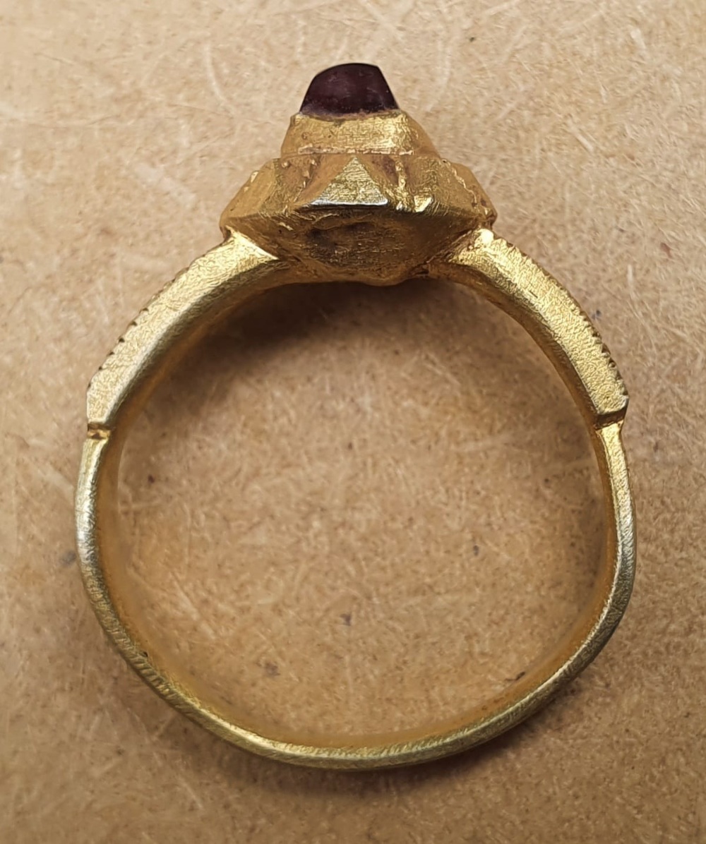 A 15thC silver-gilt finger ring with square cut garnet.