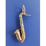 A 9ct gold pendant modelled as a saxophone with enamelled key details, 1.9" - marks rubbed.