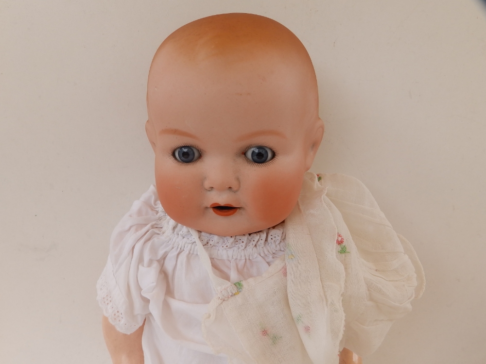 An Armand Marseille bisque head baby doll with blue paperweight eyes, open mouth, composition body -