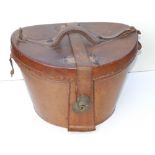 An early 20thC leather hat box containing a (distressed) top hat by Heath.