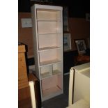 A tall slender white painted bookcase, w