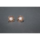 A pair of silver and simulated seed pearl flower head shaped stud earrings.