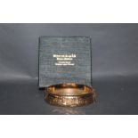 An early 20th century rose gold plated hinged bangle with engraved top and metal core. 6.