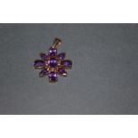 A 9ct gold and amethyst floral pattern pendant set with 9 cut stones of oval and pear shape, 3.