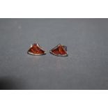 A pair of silver and amber set stud earrings of curved triangular design with cabochon stones.