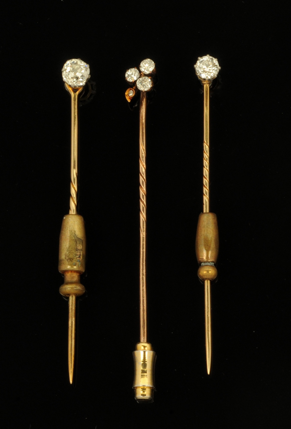Three gold coloured metal and diamond set stick pins, two set with single stones (0.2 & 0.