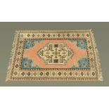 A Turkish woollen fringed rug, with centre rectangular panel and repeating line border,