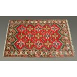 A Turkish fringed woollen rug, bearing label Turgut Koy, principal colours blue, beige and red.