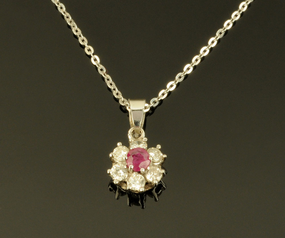 An 18 ct white gold diamond and ruby pendant, with 18 ct white gold chain, pendant diameter 8 mm.