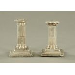 A near pair of silver candlesticks, with fluted columns and beaded square stepped bases.