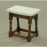 A reproduction oak joint stool, with upholstered top and piping.