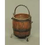 A barrel form wrought iron mounted log or coal receiver, raised on three short scroll feet.