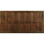 A section of old oak Wainscot panelling, the upper panels carved with geometric and circular motifs.