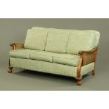 A walnut framed bergere lounge settee, with double caned sides and single caned back,