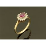 A 9 ct gold cluster ring with ruby coloured centre stone, and white stones surrounding.