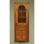 An Ipswich oak standing corner cupboard, with glazed upper section, retailed by Chapmans.