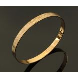 A 9 ct gold slave type bangle, with multi coloured gold inlay and textured finish,