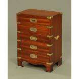 A military style mahogany bedside chest, five drawers with recessed brass handles, brass bindings,