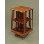 An Edwardian inlaid mahogany revolving bookcase, of serpentine outline and raised on castors.