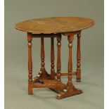 An oak drop leaf gate legged table, with turned supports and sledge feet.