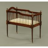 An Edwardian child's mahogany crib, with spindle turned sides on turned legs and castors.