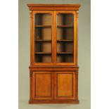 A late Victorian walnut glazed bookcase on cupboard,